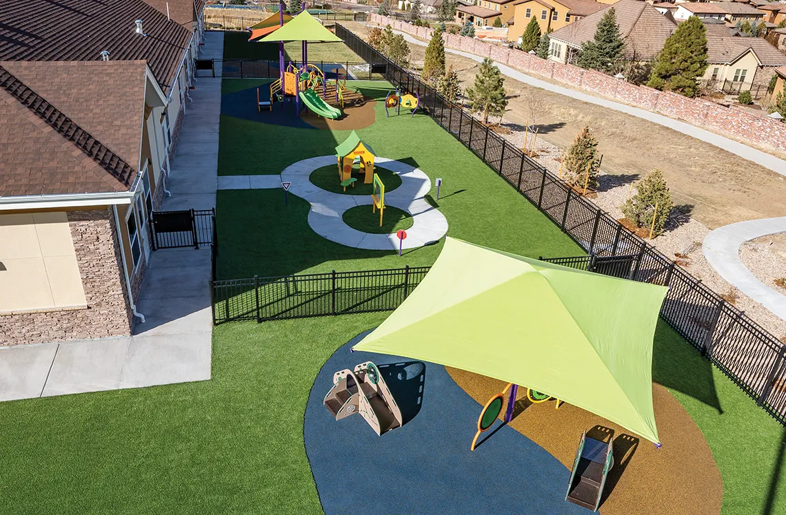 Rubber turf playground surface with shade at Kiddie Academy